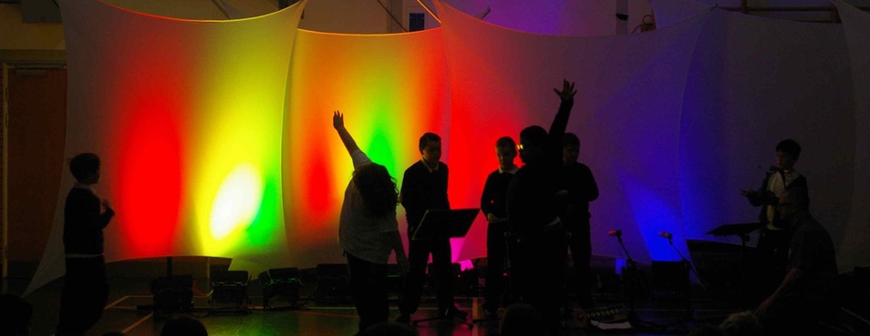 children performing in front of lit sails